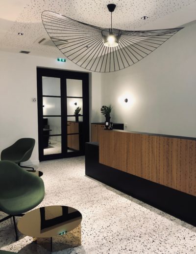 Photo du comptoir d'accueil en bois OberSound, le sol est en Terrazzo, des fauteuils en feutre vert.