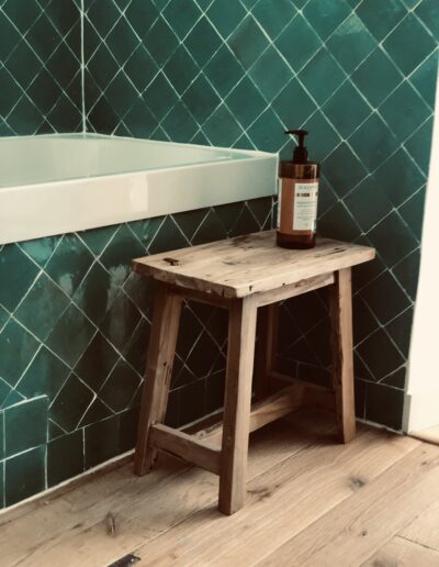 Baignoire habillée de zelliges. Parquet au sol. Tabouret en bois massif.